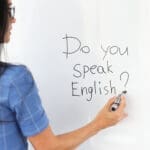 Woman teacher writes with marker do you speak english on white board. Work as translator concept