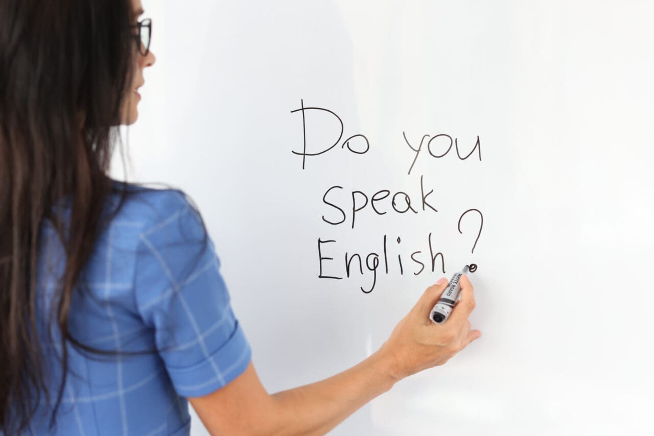 Woman teacher writes with marker do you speak english on white board. Work as translator concept