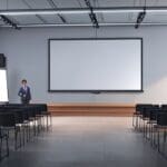 Salón de conferencias moderno con pantallas tecnológicas y un escenario listo para presentaciones