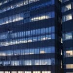 Moderno edificio de oficinas con luces brillantes en la ciudad al anochecer.