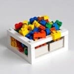 Piezas de LEGO multicolores recicladas en una mesa de oficina minimalista con fondo blanco.