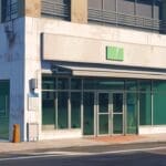 Fachada moderna de una clínica tecnológica en un entorno urbano pequeño y soleado