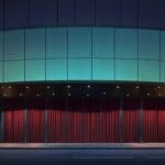 Exterior moderno de un teatro con fachada de vidrio y luz natural