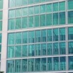 Edificio moderno con fachada de vidrio rodeado de áreas verdes, representando innovación tecnológica.