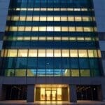 Fachada de un edificio financiero moderno al anochecer con luces encendidas