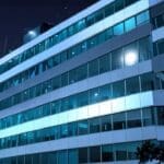 Vista de un moderno edificio corporativo tecnológico, rodeado de luces y elementos digitales