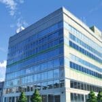 Edificio moderno de oficinas con diseño innovador y tecnología avanzada, rodeado de verde y un cielo claro