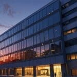 Moderno edificio corporativo con luces de oficinas encendidas al atardecer