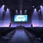 Sala de conferencias llena de gente con pantallas digitales en un evento tecnológico