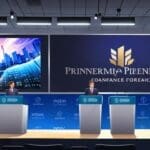 Conferencia de prensa corporativa con logos modernos y gráficos financieros en pantalla