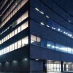 Edificio moderno de biotecnología con luces brillantes al anochecer