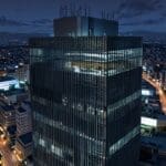 Vista aérea de un edificio moderno de oficinas en Ciudad de México con luces encendidas al anochecer, simbolizando inversión y tecnología