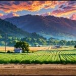 Paisaje rural con pequeñas construcciones modernas rodeadas de montañas y senderos turísticos, bajo cielo despejado