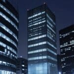 Edificios modernos en un distrito financiero europeo con luces encendidas al anochecer