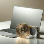 Primer plano de un hardware de criptomonedas junto a una laptop moderna en un ambiente minimalista.