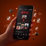 Smartphone mostrando videos verticales de Netflix en un entorno futurista en tonos naranja y negro representando experimentos de streaming y tendencias de consumo de video.